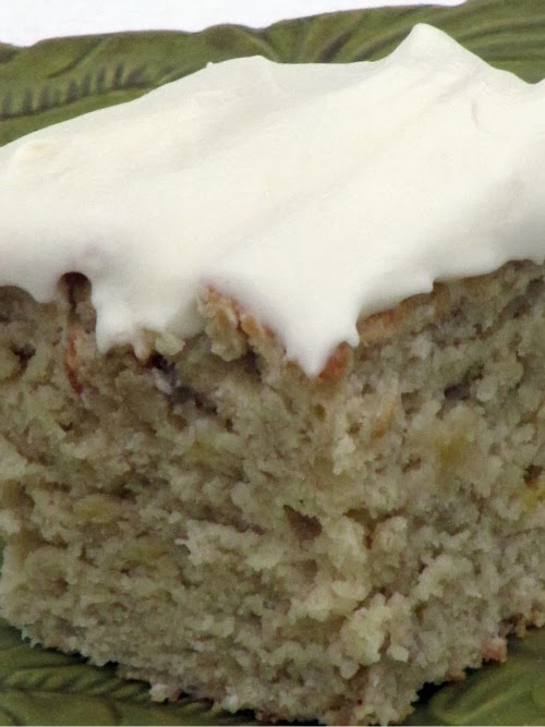 Old fashioned classic banana cake with cream cheese frosting on a green plate. 