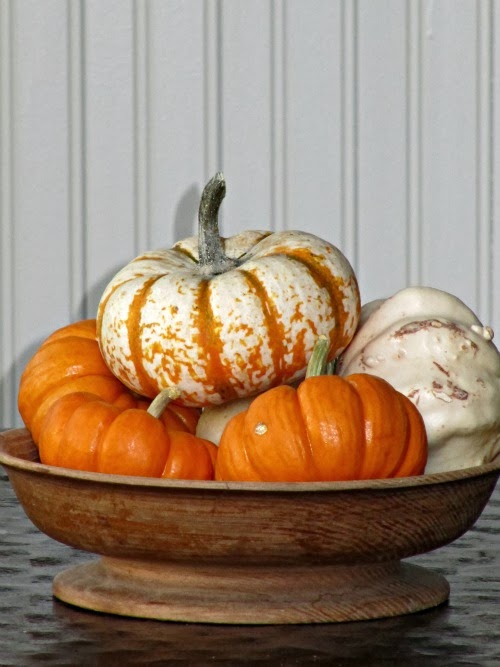 Orange and white pumpkins n a wooden bowl.