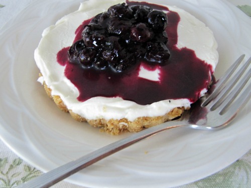 Smalle cheesecake tart with blueberries on a white plate.