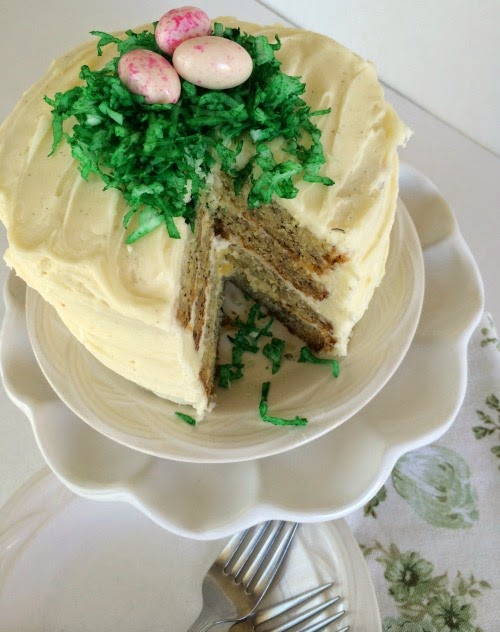 Banana cake frosted with cream cheese frosting and green coconut nut nest and 3 egg candies.