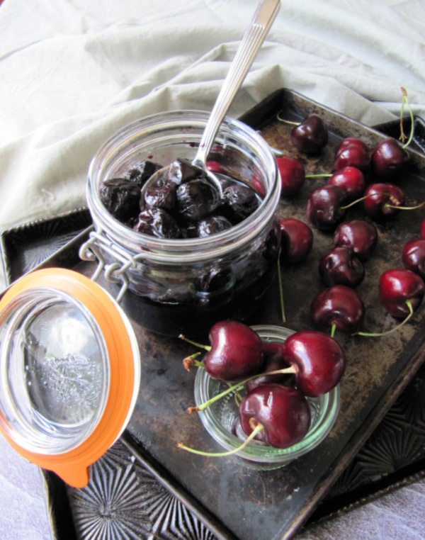 Roasted Cherries ub a jar with cherries scattered about.
