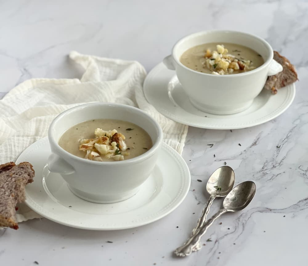 caramelized onion and cauliflower soup in white bowls on saucers.