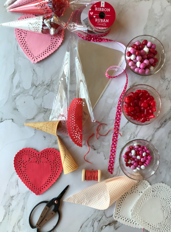 DIY Valentines Day Favors using sugar cones, doilies, candy, cellophane bags and ribbon.