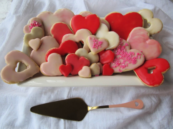 White plate piled high with pink, red and white heart shaped sugar cookies