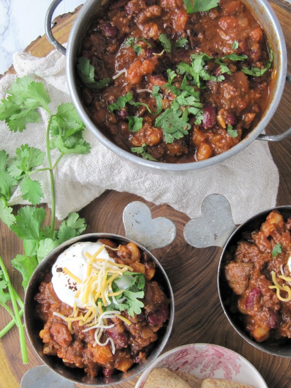 tex-mex-chili in 2 bowls and a pot with cheese and cilantro