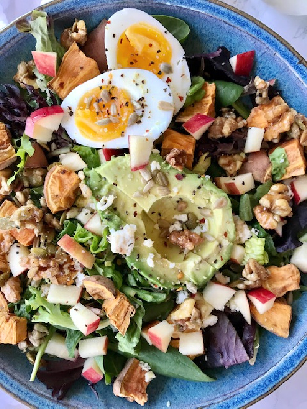 blue bowl filled with lettuce apples avocado sweet potatoes 