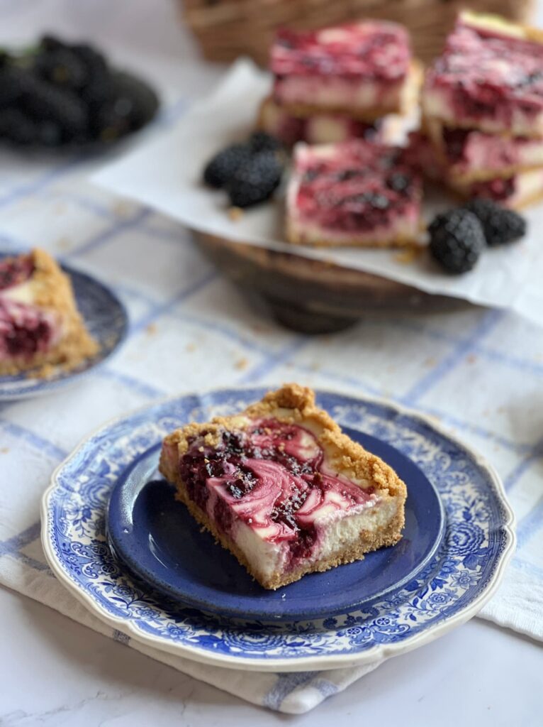 side view of blackberry cheesecake bars on blue and white transferware plates