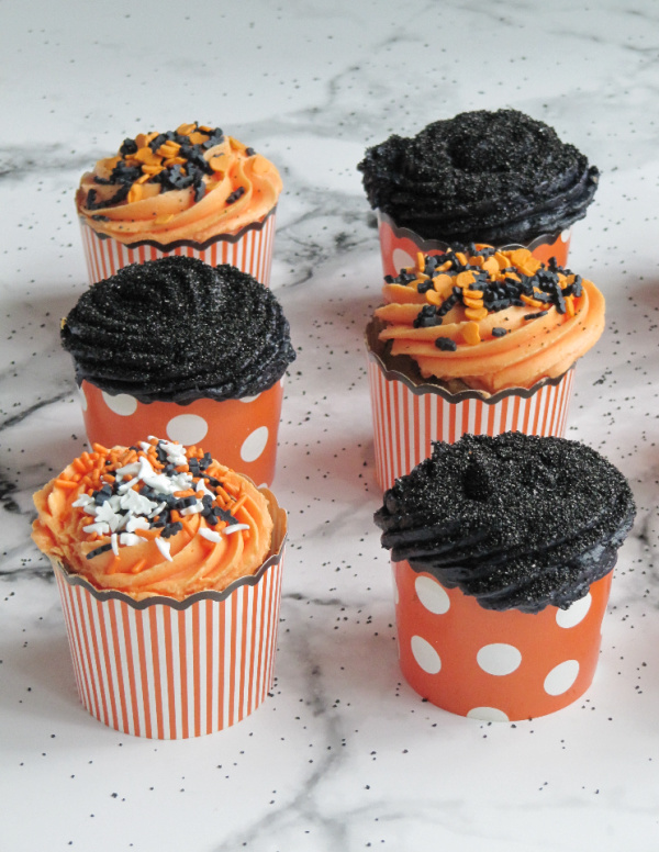 homemade pumpkin carrot cupcakes with buttercream frosting and halloween sprinkles