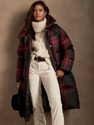 lady wearing an ivory sweater and pants with a plaid long purser jacket 