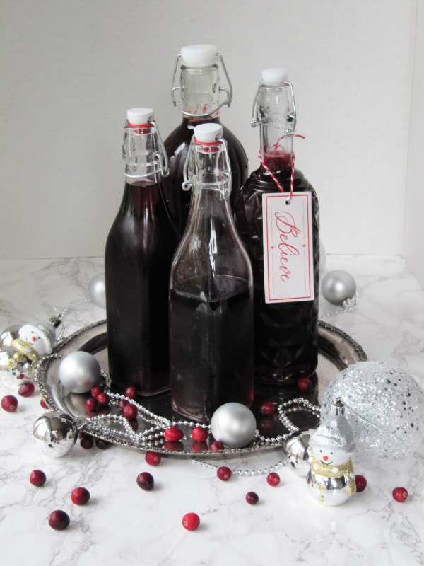4 bottles of various heights filled with burgundy liquid on a silver tray and a tag that says believe
