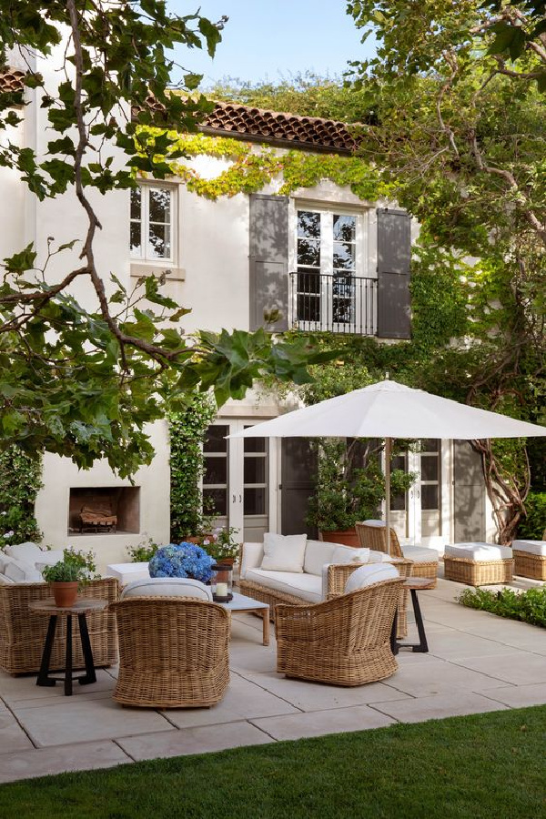 back patio filled with brown wicker chairs with white umbrella and cushions 