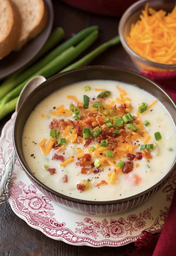 A brown bowl with potato soup topped with bacon and cheese.