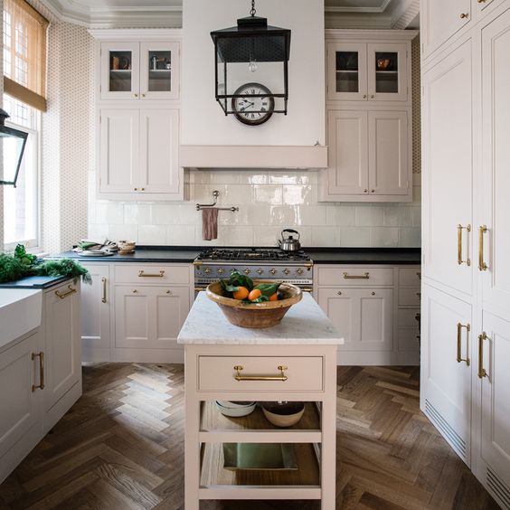 A off-white kitchen with a White Island and brown brick floors.