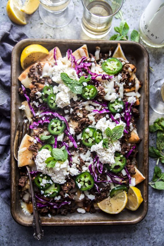 pita nachos with whipped feta cheese on a black metal pan.