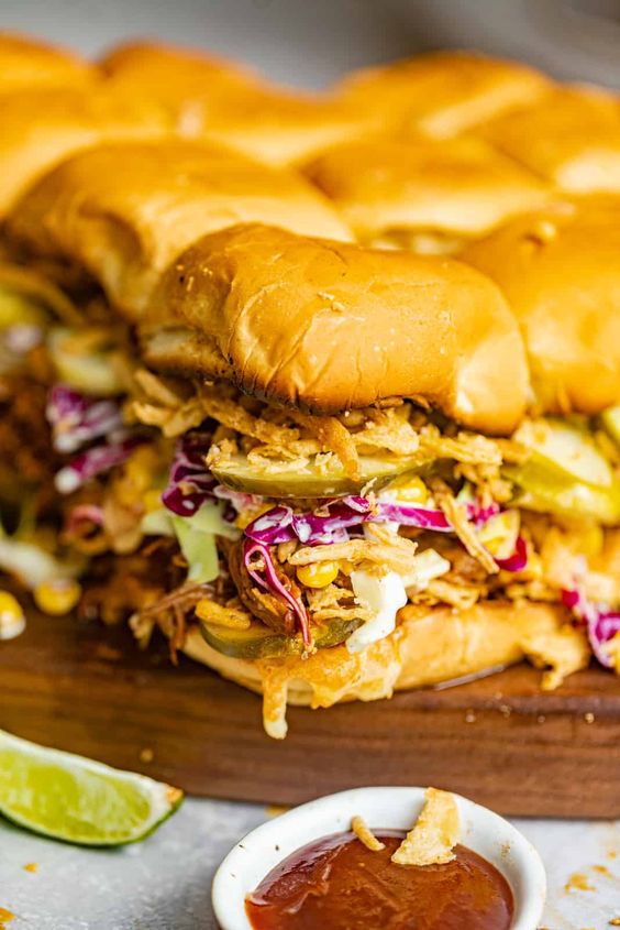 4 Pulled pork sliders on a wood board.