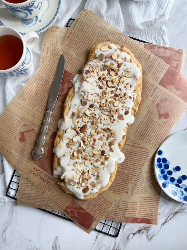 Swedish Kringler Almond Puff on a brown paper with a cup of tea.