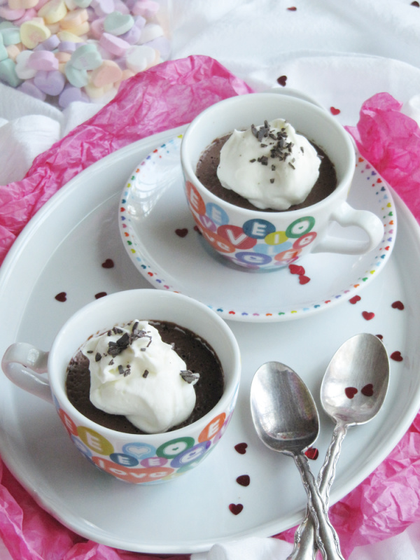 two white cups with colorful hearts sitting on a white tray filled with dark chocolate mouse and topped with whipped cream. 