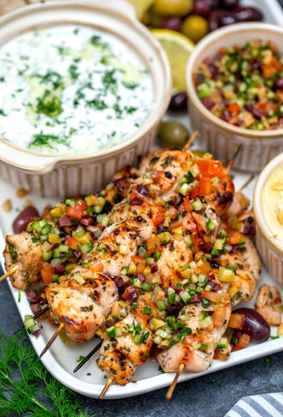 Chicken Souvlaki on a platter with condiments in small bowls. 