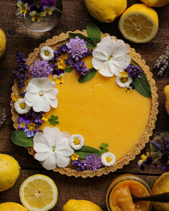 Lemon curd tart decorated with purple and white flowers.
