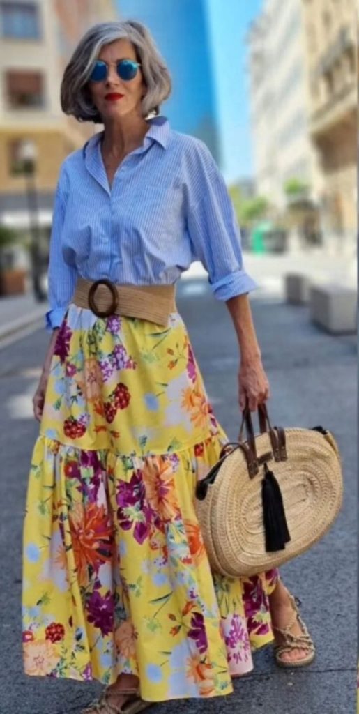 Woman wearing a yellow flowerskirt and blue blouse.