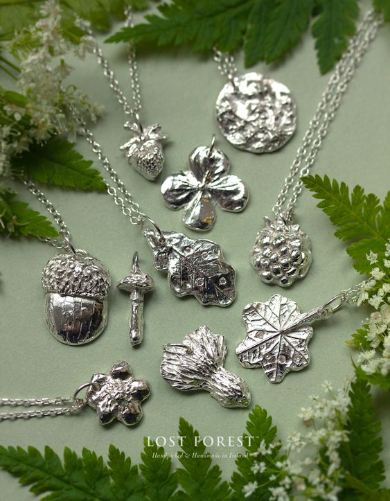 a collection of silver jewelry in the shape of mushrooms, acorns and leaves.