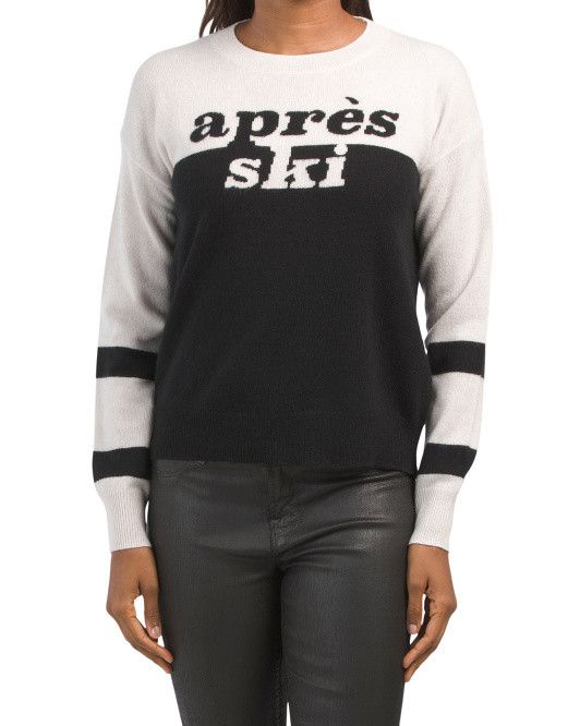 Woman wearing a black and white cashmere sweater with Apres Ski on the front. 