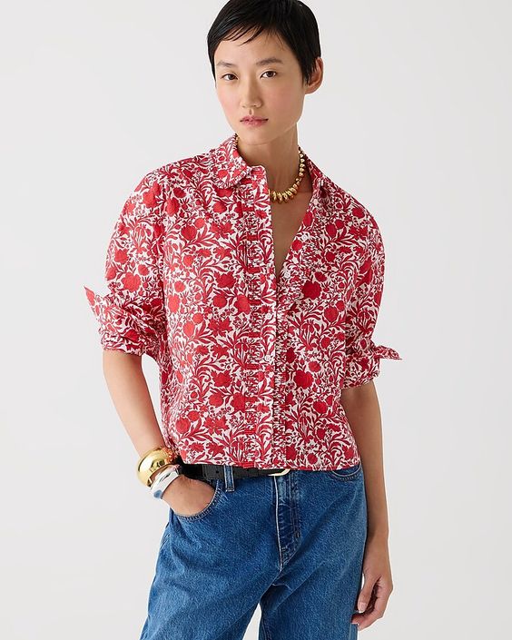 Woman wearing a red and white print blouse and jeans. 