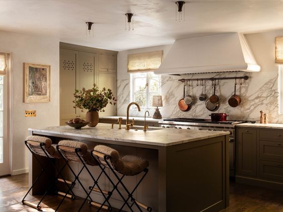 A moody green kitchen with a large wolf ranges and white plaster hood. 