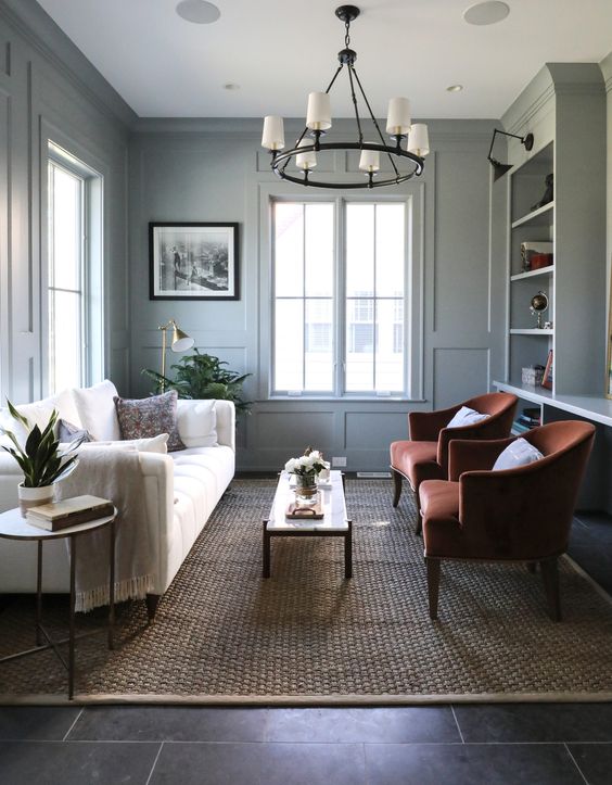 A cozy pale green living room with 2 tan leather barrel chairs and a white couch. 