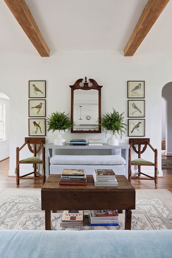 Sabbe Interior Design, a living room with a light blue sofa, 2 brown chairs a coffee table and 6 vintage prints of birds. 