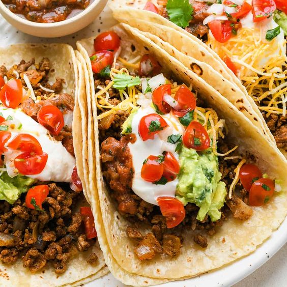Ground beef tacos on a tray with salsa. 