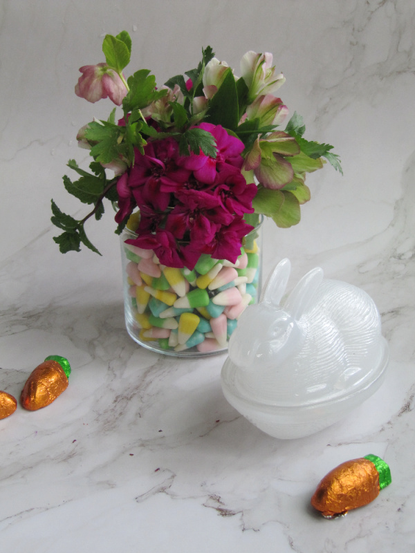 Easter-flower centerpiece-with-geraniums-and-herbs with a frosted glass bunny candy holder.