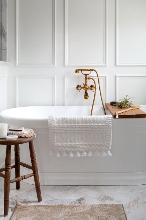 Kate Abt Design with a white free standing bathtub and walls with molding.