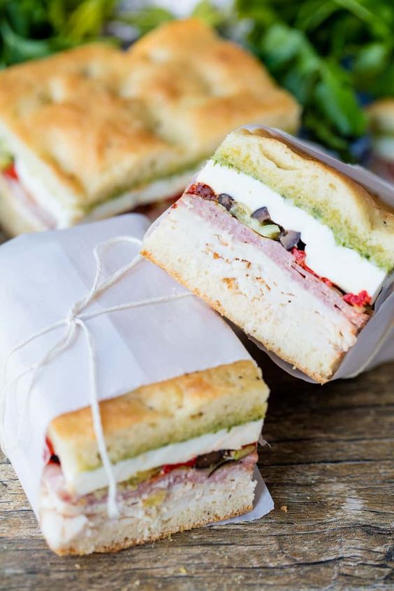 Pressed picnic sandwiches wrapped in paper and string.