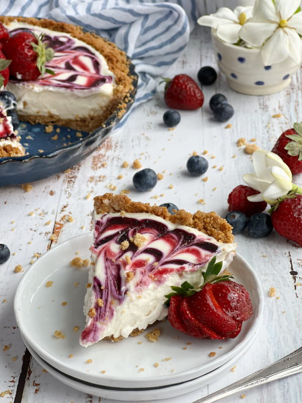 Red White and Blue No-Bake Cheesecake slices on a white plate with berries.