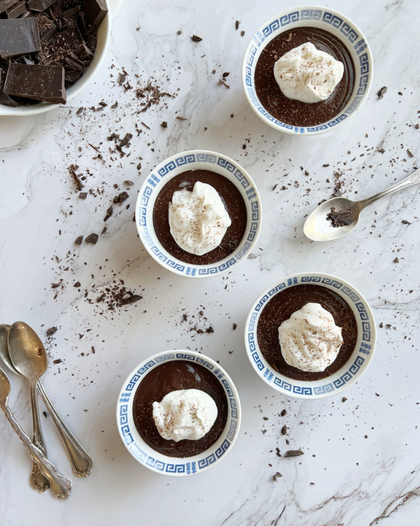 Double chocolate pudding recipe in 4 blue and white bowls with whipped cream. 