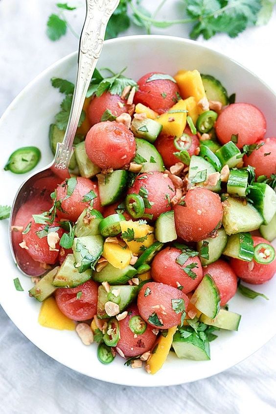 A white bowl filled with cucumber, watermelon and mango salad. 