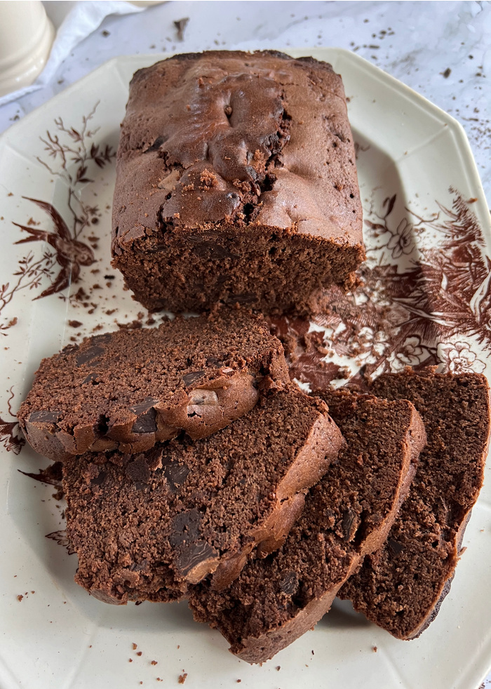 Ina Garten's Triple Chocolate Loaf Cake sliced on a white and brown ironstone platter.