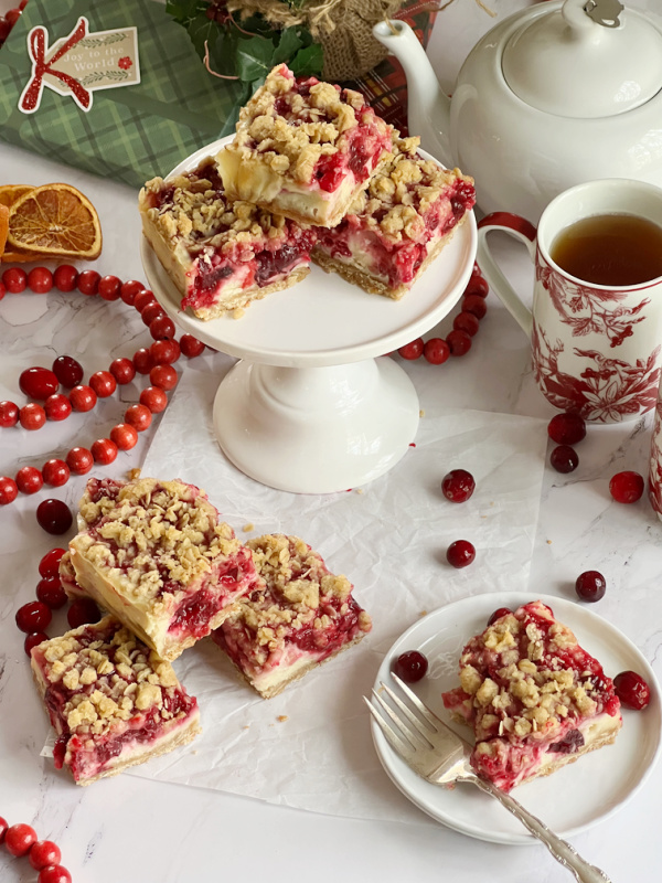 Cranberry cheesecake bars on a white cake stand. 