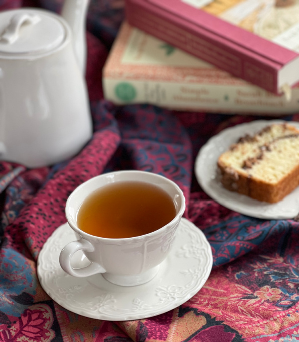 Cup of tea and books with a piece of cinnamon bread.