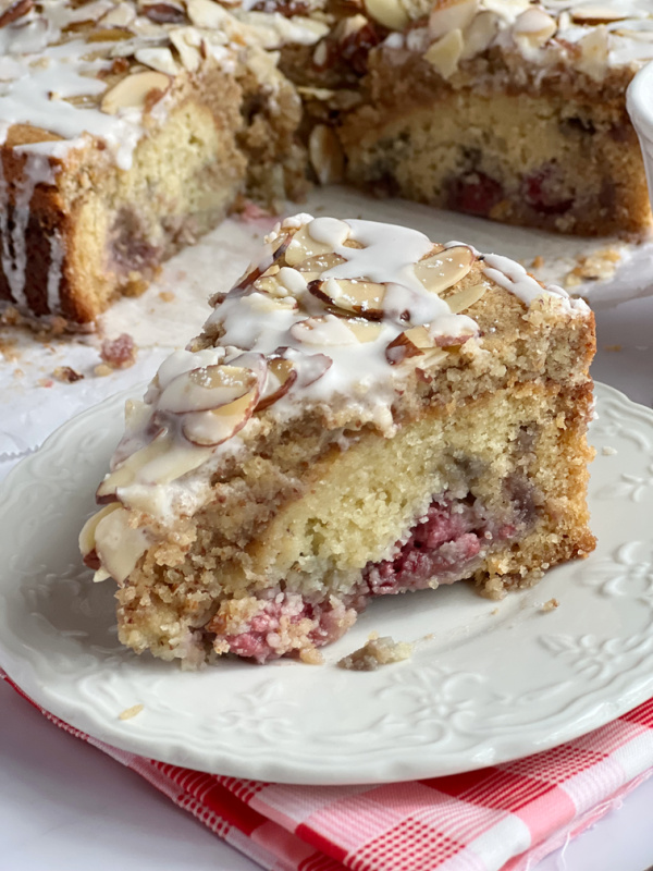 Slice of Raspberry Almond Frangipane Coffee Cake on a white plate and a pink check napkin.