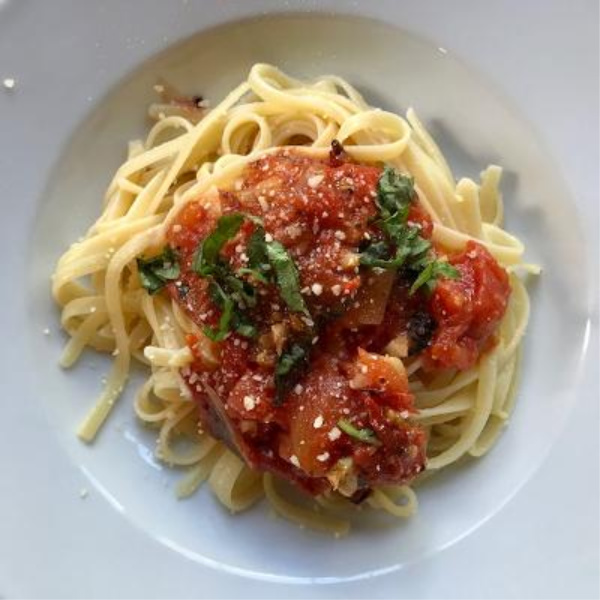 Summer tomato sauce over pasta in a white bowl.