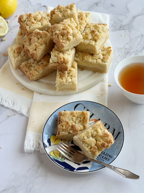 lemon bars with crumb topping on a blue plate.