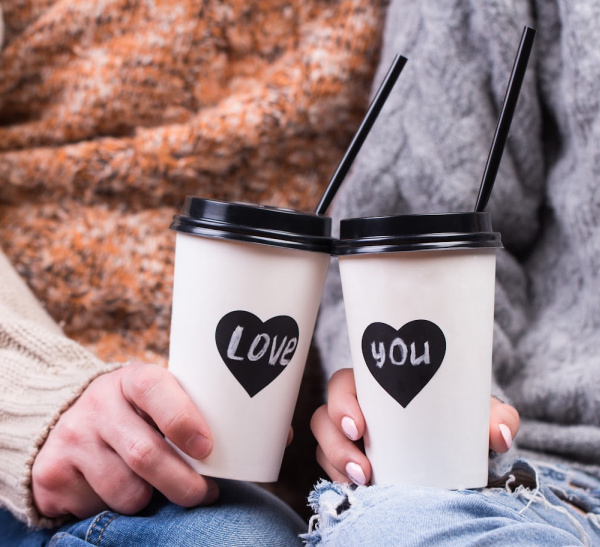midlife couple drinking coffee with love you on the cups.