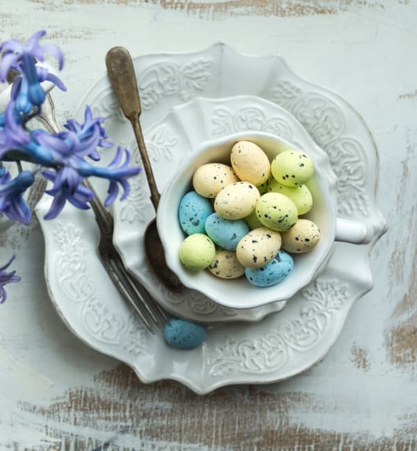 vintage white cup and saucer filled with colorful easter eggs
